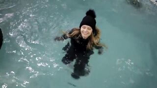 wetlook girl with winter clothes swims in the pool